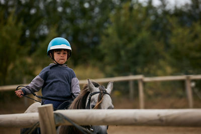 5-year-old girl riding on a horse, in a hipico club. infalltil sport concept
