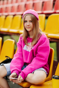 A teenage girl sits on the school bleachers and writes a message on her phone in her free time