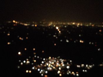 Defocused image of illuminated city against sky at night