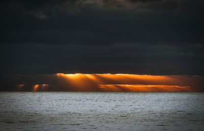 Scenic view of sea against dramatic sky during sunset