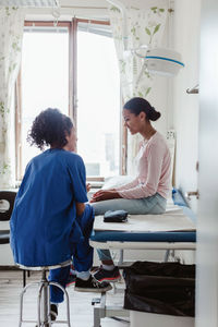 Smiling patient and female doctor discussing in medical room