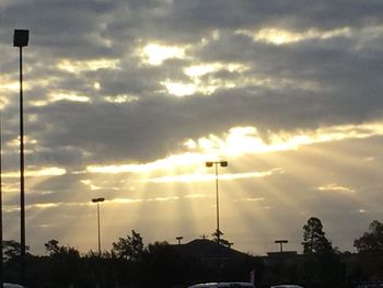 Silhouette of street light against cloudy sky