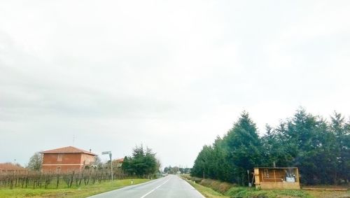 Road by houses against sky