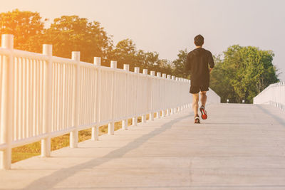 Rear view of man walking on footpath