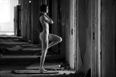 Side view of naked woman standing at abandoned room