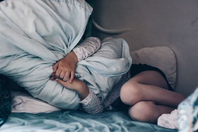 Midsection of woman with blanket relaxing on bed at home