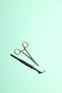 High angle view of scissors and angled mirror over green background