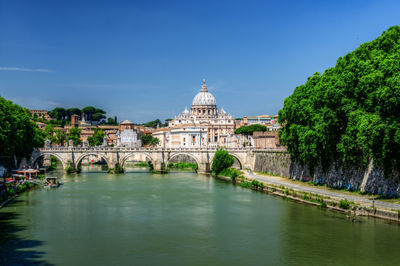 View of building by river against blue sky