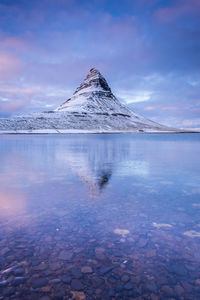 Scenic view of lake by snow covered mountain against sky