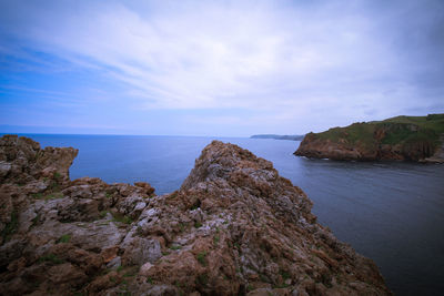 Rock formations by sea against sky