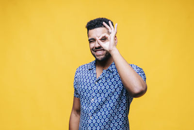 Portrait of smiling young man against yellow background