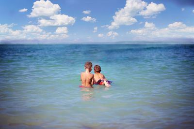 Friends swimming in sea against sky