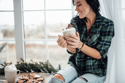 Smiling woman holding hot chocolate at home