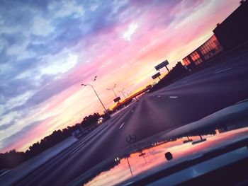 Cars on road against sky at sunset