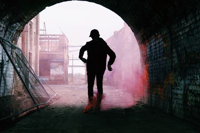 Rear view of silhouette man standing in tunnel