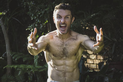 Portrait of young man with arms raised and screaming expression on his face.