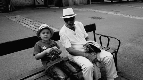 High angle portrait of grandfather with grandson sitting on bench