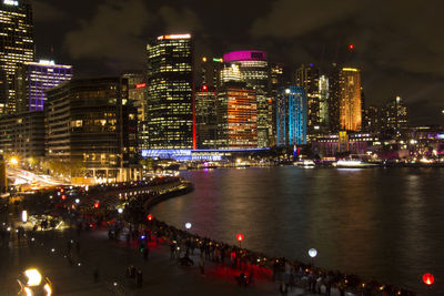 River by illuminated city skyline against sky at night