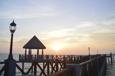 Pier on street by sea against sky during sunset