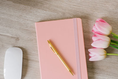 Women home office desk. workspace with pink tulip flowers, notebook