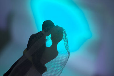 Low angle view of man holding hands against blue background