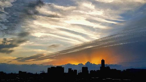 Silhouette cityscape against sky during sunset