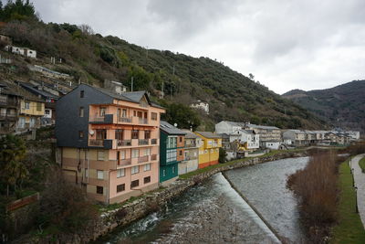 Houses by river and buildings against sky