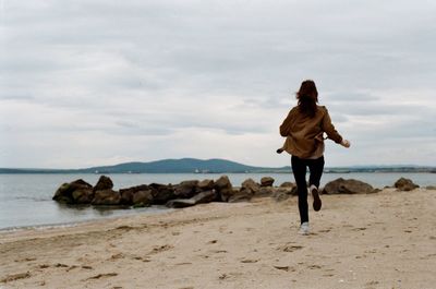 Full length of young woman on beach against sky