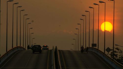 Cars on street against sky during sunset