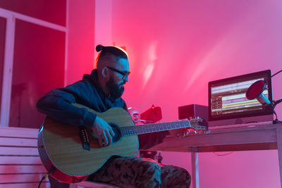 Man playing guitar against wall