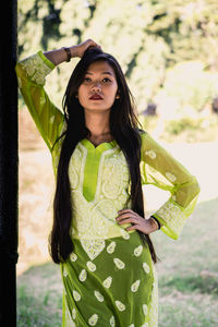 Portrait of young woman while standing by railing at park