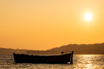 Silhouette boat in sea against sky during sunset