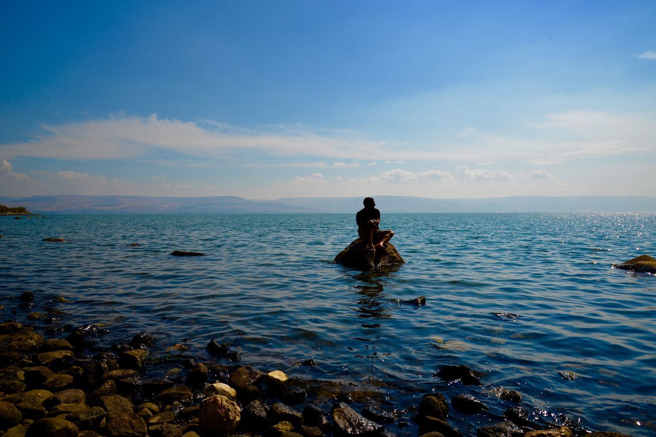 sea, water, horizon over water, sky, tranquility, scenics, tranquil scene, beauty in nature, leisure activity, lifestyles, nature, rock - object, silhouette, full length, beach, men, blue, idyllic