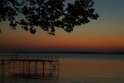 Silhouette tree by sea against sky during sunset