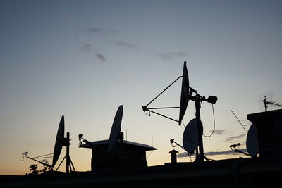 Low angle view of silhouette cranes against sky at sunset