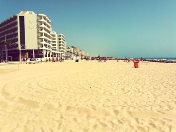 People on beach against clear blue sky