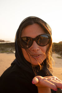 Portrait of young woman wearing sunglasses against clear sky