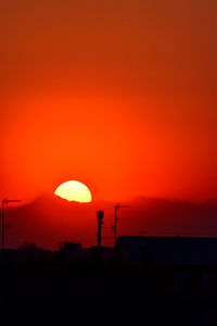 Silhouette buildings against orange sky