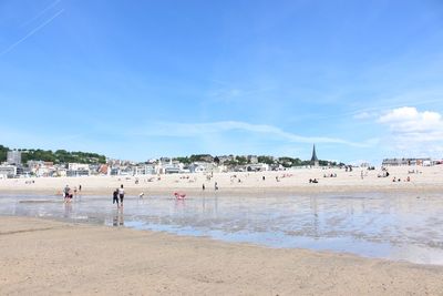 People at beach against blue sky