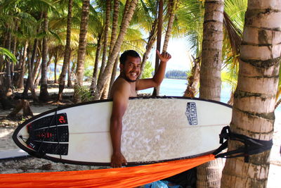 Portrait of smiling man holding surfboard at beach