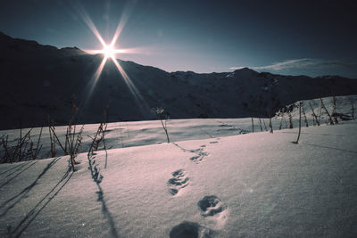 Scenic view of snow covered mountains against bright sun