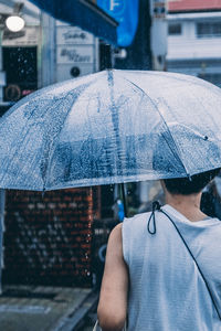 Rear view of man holding umbrella during rainy season