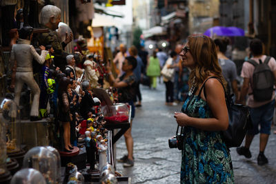 Side view of woman looking at statues in market