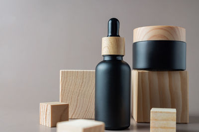 Black cosmetic dropper bottle and cream jar mockup on wooden cubes background. 