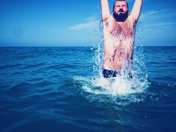 Shirtless man swimming in sea