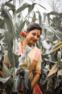 Portrait of smiling beautiful woman wearing traditional clothing while standing amidst plants