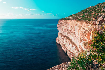 Rock formations by sea against blue sky