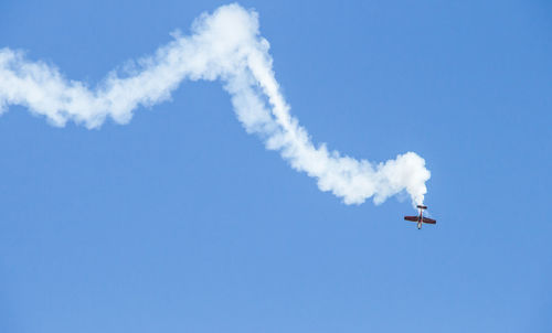 Low angle view of airplane flying against clear blue sky