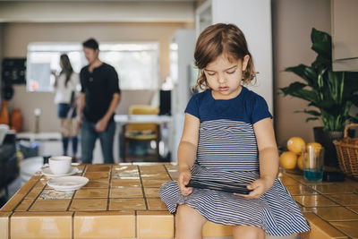 Daughter using phone while parents standing in background