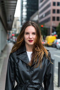 Portrait of beautiful woman wearing black jacket standing in city